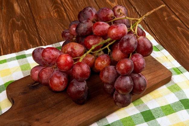 Zijaanzicht van een tros druiven op een houten bord op rustieke tafel