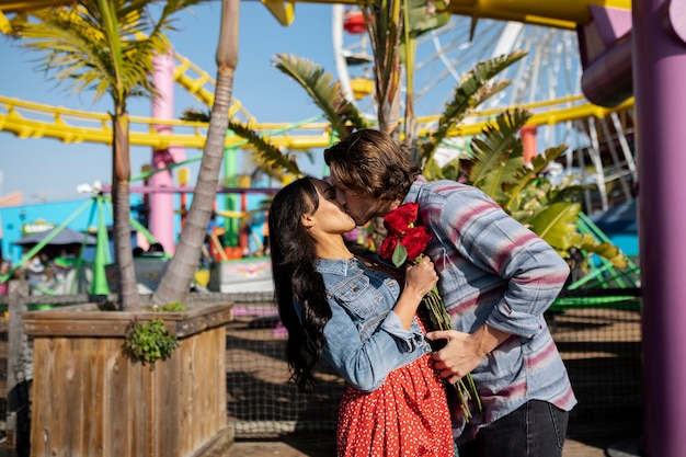 Zijaanzicht van een zoenend koppel tijdens een date in het pretpark