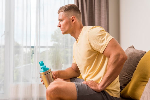 Zijaanzicht van fit man ontspannen op de bank na het trainen