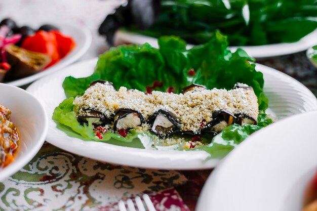 Zijaanzicht van gebakken aubergine rolt met noten en knoflook op sla