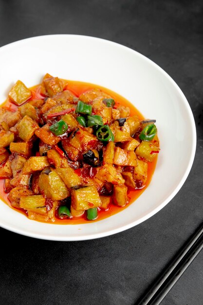 Zijaanzicht van gebakken aubergines en aardappelen met chili saus in een plaat