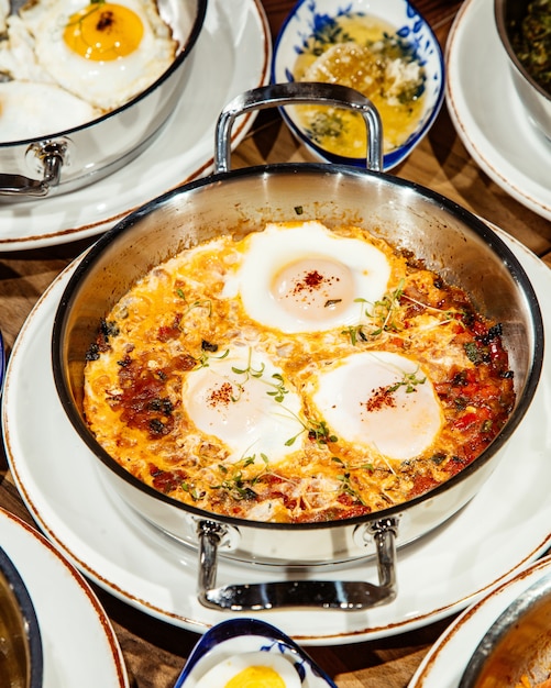 Gratis foto zijaanzicht van gebakken eieren met tomaten, ui en kip in een pan