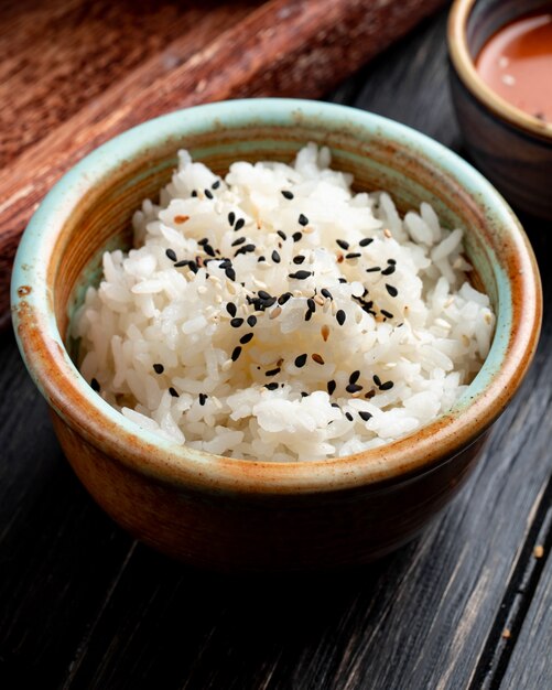 Zijaanzicht van gekookte rijst met zwarte zaden in een klei kom op hout