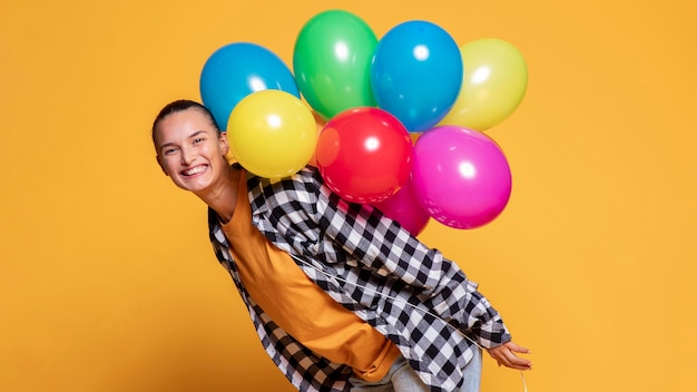 Zijaanzicht van gelukkige vrouw met veelkleurige ballonnen