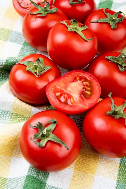 Zijaanzicht van gesneden en hele tomaten op geruite doek