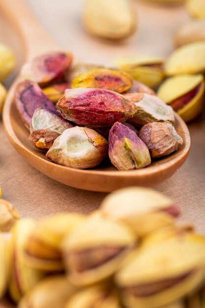 Zijaanzicht van gezouten geroosterde pistachenoten een houten lepel op oude document textuurachtergrond