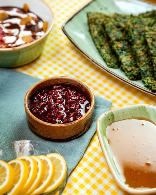 Zijaanzicht van granaatappelsaus in kom en en honing op de tafel