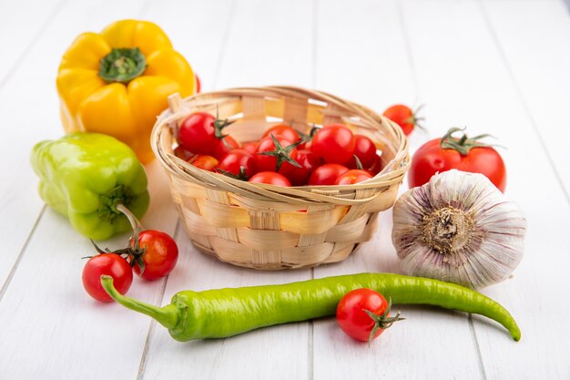 Zijaanzicht van groenten als mandje tomaat met de bol van het peperknoflook en tomaten rond op hout