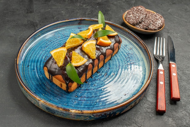 Zijaanzicht van heerlijke cake en koekjes met mes en vork op zwarte lijst