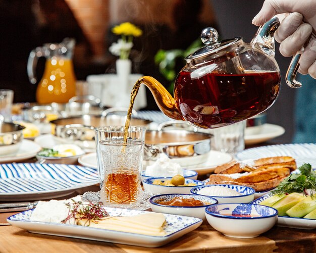 Zijaanzicht van het gieten van zwarte thee in een glas