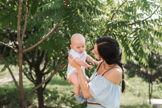 Gratis foto zijaanzicht van het jonge vrouw spelen met baby in de tuin