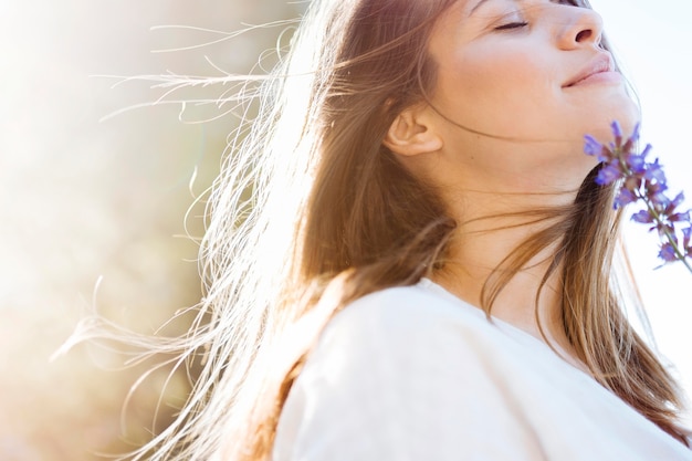 Zijaanzicht van het mooie vrouw stellen met bloem