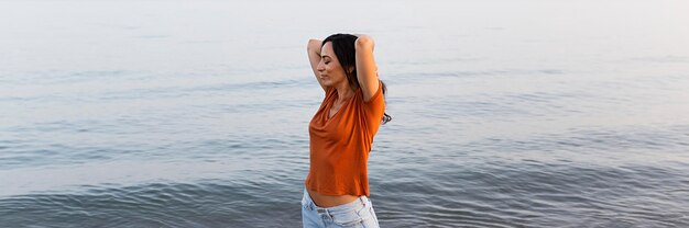 Zijaanzicht van het onbezorgde vrouw stellen aan het strand