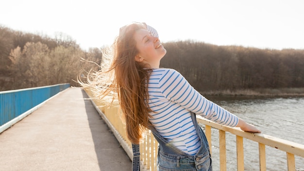 Zijaanzicht van het onbezorgde vrouw stellen op brug