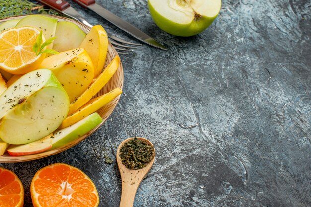 Zijaanzicht van het verzamelen van vers natuurlijk biologisch fruit op een wit bord bestekset kaneellimoenen op een donkere achtergrond