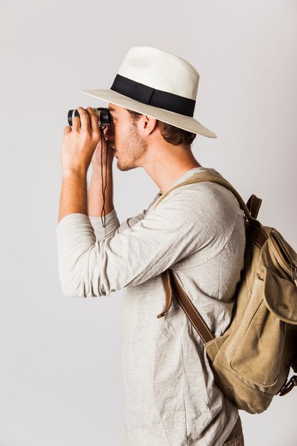 Zijaanzicht van hipster man kijkend door een verrekijker