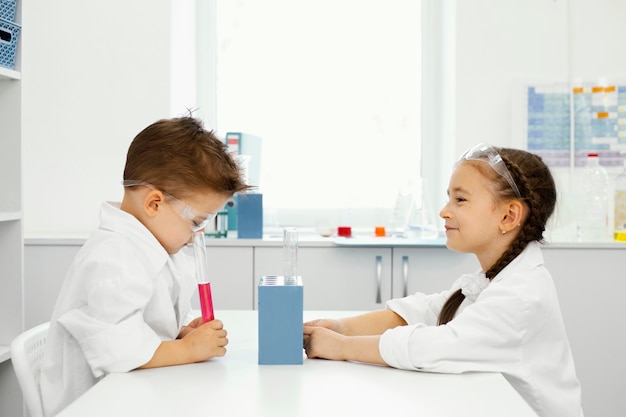 Zijaanzicht van jongen en meisje wetenschappers in het laboratorium met veiligheidsbril