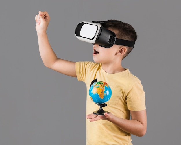 Zijaanzicht van jongen met de holdingsbol van de virtuele werkelijkheidshoofdtelefoon