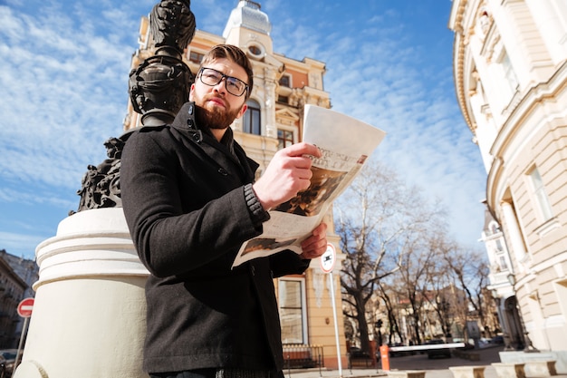 Zijaanzicht van knappe man in jas met krant