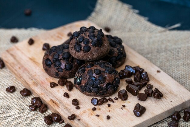 Zijaanzicht van koekjes en chocolade op scherpe raad op jute en blauwe achtergrond