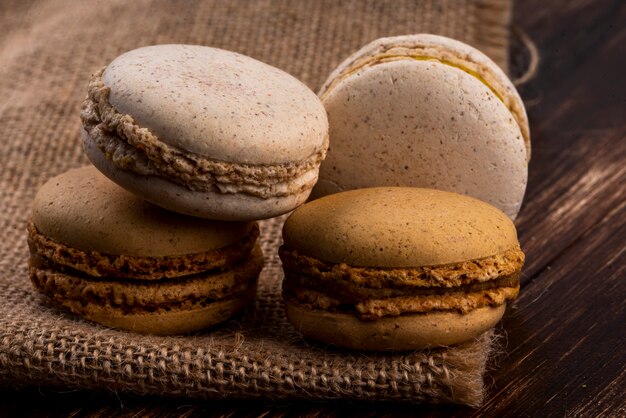 Zijaanzicht van koekjessandwiches op jute en houten achtergrond