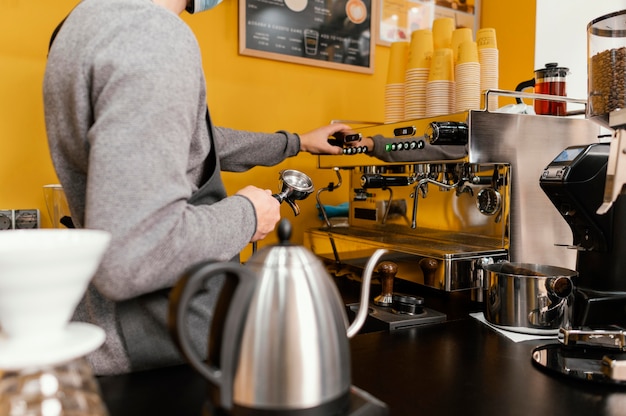 Zijaanzicht van mannelijke barista die in het koffiehuis werkt