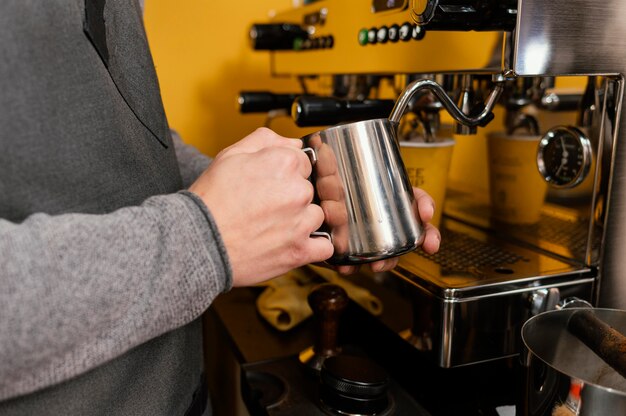 Zijaanzicht van mannelijke barista die melk opschuimt