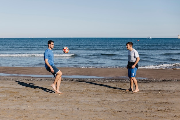 Zijaanzicht van mensen die voetbal spelen bij het strand