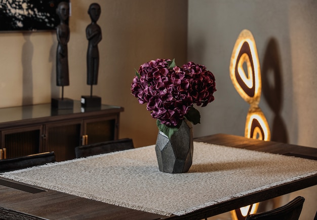 Zijaanzicht van moderne zwarte vaas met paarse bloemen op een tafellaken op tafel