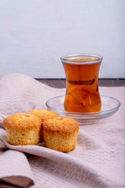 Zijaanzicht van muffins met armudu glas thee op een tafelkleed