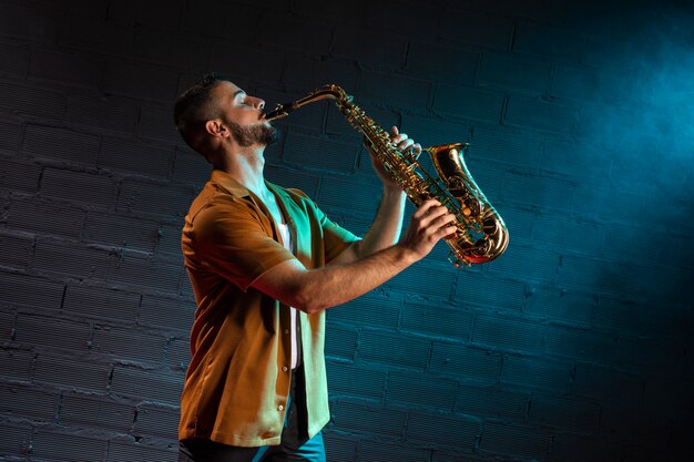 Zijaanzicht van musicus die de saxofoon met exemplaarruimte speelt