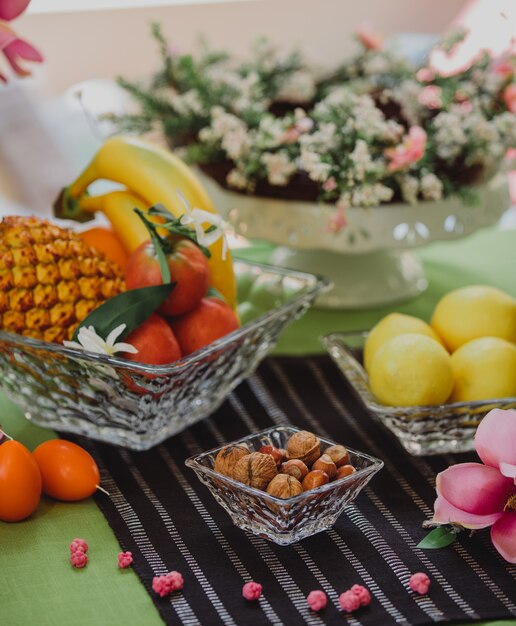 Zijaanzicht van noten en fruit in de decoratieve vazen op tafel