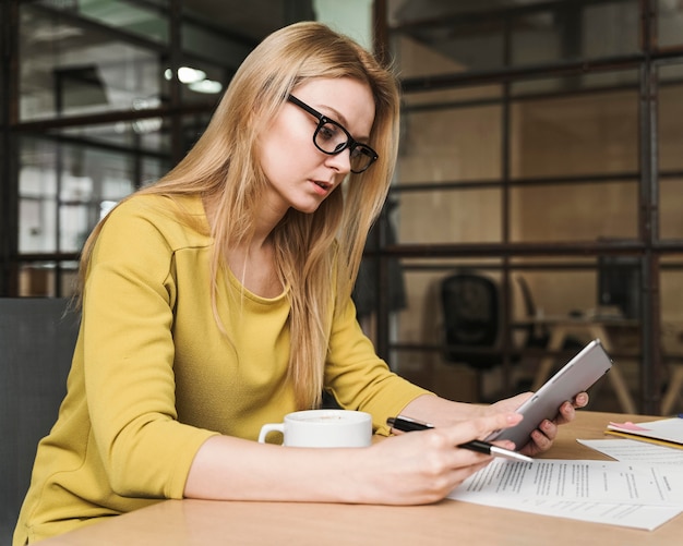 Gratis foto zijaanzicht van onderneemster die bij bureau werkt