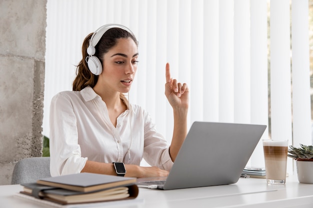 Gratis foto zijaanzicht van onderneemster die met hoofdtelefoons en laptop werkt