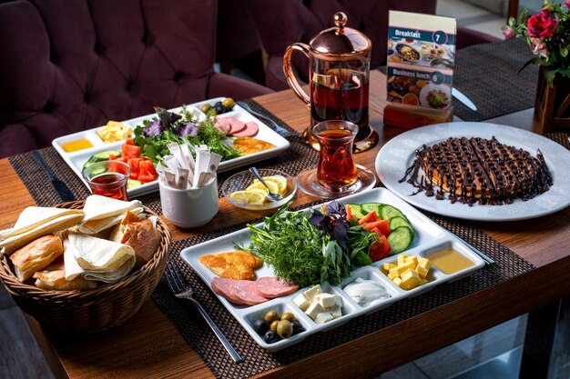 Zijaanzicht van ontbijttafel geserveerd met verschillende voedsel dessert en thee
