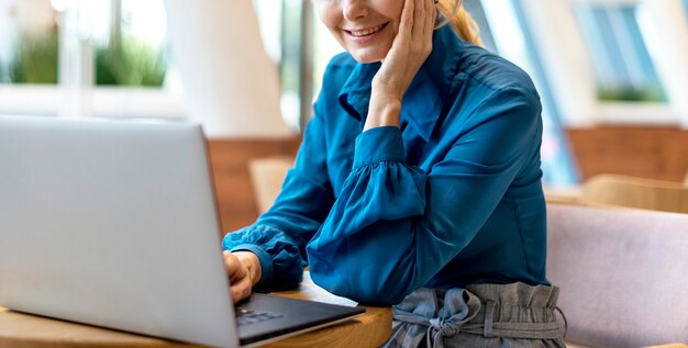 Zijaanzicht van oudere bedrijfsvrouw die aan laptop werkt