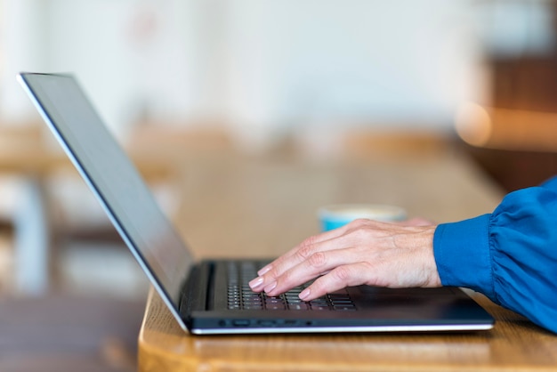 Zijaanzicht van oudere bedrijfsvrouw die aan laptop werkt