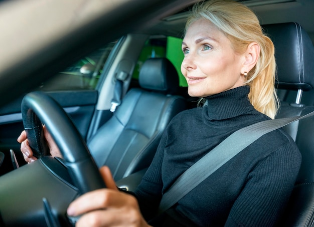 Gratis foto zijaanzicht van oudere zakenvrouw rijden auto