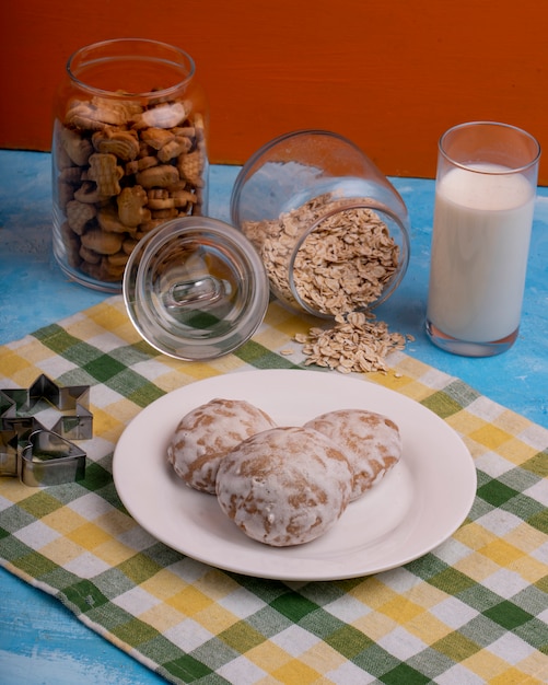 Zijaanzicht van peperkoek cookies op een witte plaat en een stervormige cookie cutter op de keukentafel