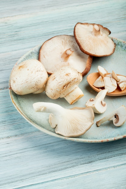 Zijaanzicht van plaat met hele verse champignons op rustieke houten oppervlak