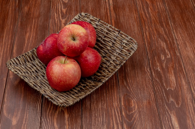 Zijaanzicht van rode appels in mand plaat op houten oppervlak met kopie ruimte