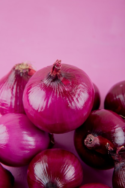 Zijaanzicht van rode uien op paarse achtergrond met kopie ruimte