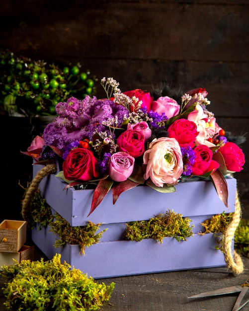 Zijaanzicht van roze en lila kleur rozen bloemen samenstelling in houten kist