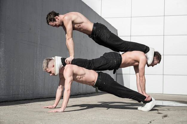 Zijaanzicht van shirtless hiphopdansers buiten