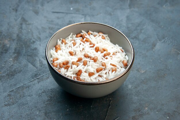 Zijaanzicht van smakelijke rijstmaaltijd met bonen in een bruine kleine pot op blauwe achtergrond