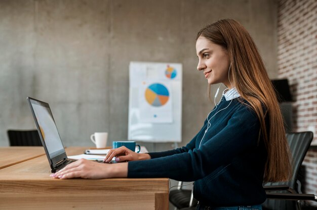 Zijaanzicht van smileyvrouw die met laptop voor een vergadering voorbereidingen treffen