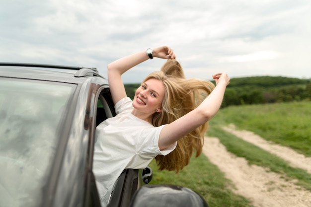 Zijaanzicht van smileyvrouw die van een autorit genieten