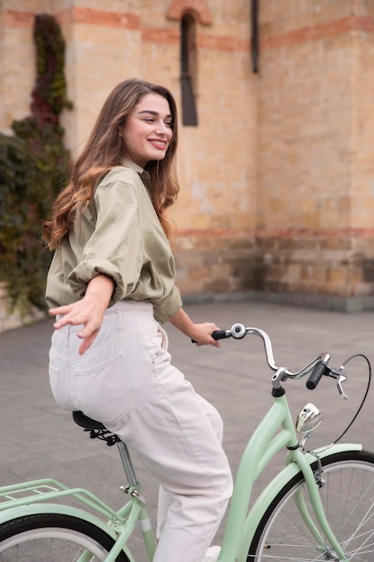 Zijaanzicht van smileyvrouw in de stad die een fiets berijdt