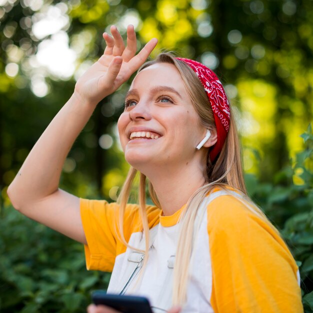 Zijaanzicht van smileyvrouw in openlucht met smartphone