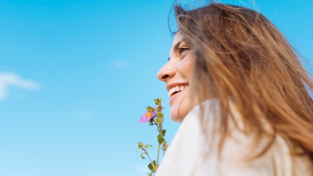 Gratis foto zijaanzicht van smileyvrouw met exemplaarruimte en bloem